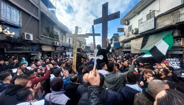 Християни от Сирия вдигат кръстове по време на митинг в района Дувейлаах в Дамаск на 24 декември 2024 г., за да протестират срещу изгарянето на коледна елха близо до Хама в централна Сирия. | Луай Бешара/AFP чрез Getty Images
